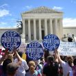 A crowd holding signs that say "KEEP ABORTION LEGAL" in front of a large building, likely a courthouse, during a protest. A crowd holding signs that say "KEEP ABORTION LEGAL" in front of a large building, likely a courthouse, during a protest.