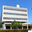 A modern university building with a blue sky and greenery in the foreground. A modern university building with a blue sky and greenery in the foreground.
