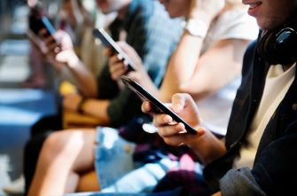Group of students sitting together, each using their smartphones.