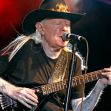 Johnny Winter performing on stage with a guitar, wearing a hat and black shirt. Johnny Winter performing on stage with a guitar, wearing a hat and black shirt.