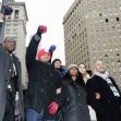 A group of individuals raising their fists in solidarity, possibly advocating for social justice, in an urban environment. A group of individuals raising their fists in solidarity, possibly advocating for social justice, in an urban environment.