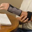 A man wearing an arm brace while typing on a keyboard. A man wearing an arm brace while typing on a keyboard.