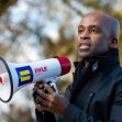 A man holding a megaphone while speaking at a rally or event. A man holding a megaphone while speaking at a rally or event.
