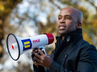 A man holding a megaphone while speaking at a rally or event.