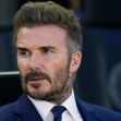David Beckham in a formal setting, wearing a suit and sitting in a sports environment. David Beckham in a formal setting, wearing a suit and sitting in a sports environment.