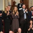 A group of individuals, including family members and advisors, clapping and attending an event in a formal setting. A group of individuals, including family members and advisors, clapping and attending an event in a formal setting.