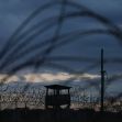 View of a guard tower surrounded by barbed wire at the Guantanamo Bay detention facility during dusk. View of a guard tower surrounded by barbed wire at the Guantanamo Bay detention facility during dusk.