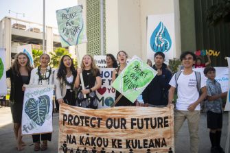 A group of young people holding signs and banners advocating for climate action and environmental preservation.