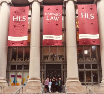 Students outside Harvard Law School during orientation, with banners showcasing the school.