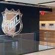 NHL logo displayed in the lobby area of the NHL headquarters, featuring a modern design with a glass railing and framed photographs on the wall. NHL logo displayed in the lobby area of the NHL headquarters, featuring a modern design with a glass railing and framed photographs on the wall.