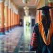 A graduate in academic regalia walking through a corridor in an educational institution. A graduate in academic regalia walking through a corridor in an educational institution.