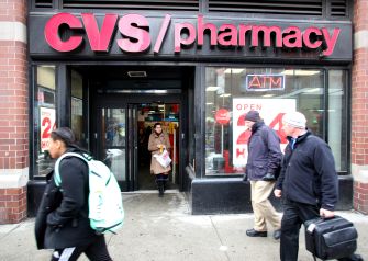 Image of a CVS pharmacy storefront with people walking by.