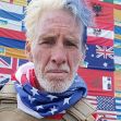 A man with a patriotic outfit and facial expression standing in front of a wall of international flags. A man with a patriotic outfit and facial expression standing in front of a wall of international flags.