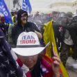 A crowd of protesters at the Capitol during the riots, with one individual wearing a "TEAM TRUMP" hat in the foreground. A crowd of protesters at the Capitol during the riots, with one individual wearing a "TEAM TRUMP" hat in the foreground.