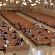 A nearly empty church interior with a few congregants seated in the pews, observing social distancing measures. A nearly empty church interior with a few congregants seated in the pews, observing social distancing measures.
