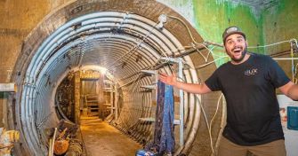A man gesturing enthusiastically inside a renovated missile silo, showcasing its interior features.