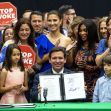 A group of people, including children, gathers around Florida Governor Ron DeSantis as he holds a signed document related to the "Stop WOKE Act," with signs displaying the phrase "STOP WOKE" in the background. A group of people, including children, gathers around Florida Governor Ron DeSantis as he holds a signed document related to the "Stop WOKE Act," with signs displaying the phrase "STOP WOKE" in the background.