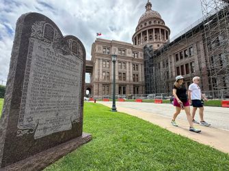 Monument displaying the Ten Commandments in front of a government building, with pedestrians walking by.