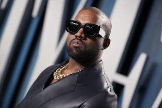 Kanye West wearing sunglasses and a stylish outfit at an event.