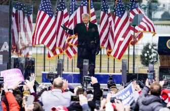 Former President Donald Trump speaking at a rally with American flags in the background.