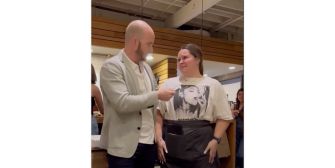 A man hands a large tip to a waitress at a restaurant as the two share a moment of gratitude.