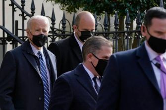 President Biden and advisors walking outdoors, all wearing masks.