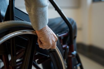 A close-up of a hand gripping the wheel of a wheelchair, symbolizing the impact of paralysis.