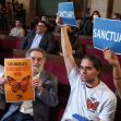 A group of supporters holding signs advocating for Los Angeles to be a sanctuary city during a city council meeting. A group of supporters holding signs advocating for Los Angeles to be a sanctuary city during a city council meeting.