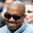 Kanye West wearing sunglasses and smiling, surrounded by a crowd. Kanye West wearing sunglasses and smiling, surrounded by a crowd.