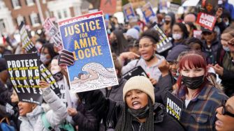 A group of protesters holding signs demanding justice for Amir Locke during a rally.