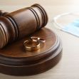 A gavel, wedding rings, and a face mask arranged on a table, symbolizing marriage and divorce during the COVID-19 pandemic. A gavel, wedding rings, and a face mask arranged on a table, symbolizing marriage and divorce during the COVID-19 pandemic.