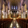 Interior view of a large church with ornate architecture, stained glass windows, and rows of empty pews. Interior view of a large church with ornate architecture, stained glass windows, and rows of empty pews.