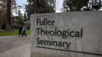Signage for Fuller Theological Seminary at its campus, with individuals walking in the background.