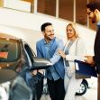 A couple interacting with a car salesman at a dealership, looking at a vehicle. A couple interacting with a car salesman at a dealership, looking at a vehicle.