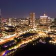 Aerial view of the Baltimore skyline at night, showcasing the city's illuminated buildings and harbor. Aerial view of the Baltimore skyline at night, showcasing the city's illuminated buildings and harbor.