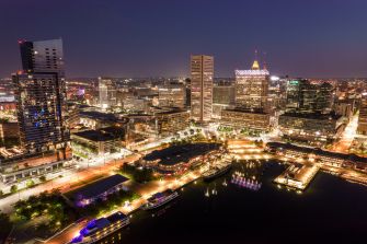 Aerial view of the Baltimore skyline at night, showcasing the city's illuminated buildings and harbor.