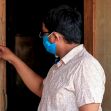 A person wearing a mask reading an eviction notice while standing at a doorway. A person wearing a mask reading an eviction notice while standing at a doorway.