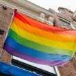 A rainbow flag waving in front of a brick building. A rainbow flag waving in front of a brick building.