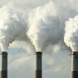 Smoke billowing from industrial chimneys against a cloudy blue sky. Smoke billowing from industrial chimneys against a cloudy blue sky.
