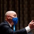 A man in a suit gesturing while speaking, wearing a blue face mask, during a congressional hearing. A man in a suit gesturing while speaking, wearing a blue face mask, during a congressional hearing.