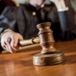 A judge holding a gavel in a courtroom setting. A judge holding a gavel in a courtroom setting.