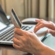 A person's hand holding a credit card while using a laptop. A person's hand holding a credit card while using a laptop.