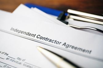 Document labeled "Independent Contractor Agreement" with pens and a clipboard in the background.