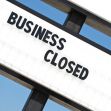 A sign that reads "BUSINESS CLOSED" against a blue sky background. A sign that reads "BUSINESS CLOSED" against a blue sky background.