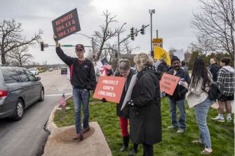 Protesters holding signs related to a lawsuit against Linn-Mar School District's gender identity policy.