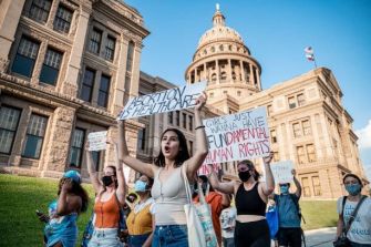 A group of protesters holding signs advocating for reproductive rights outside a government building.