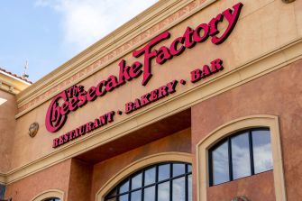 Signage of The Cheesecake Factory restaurant, featuring its name prominently along with the terms "Restaurant," "Bakery," and "Bar."