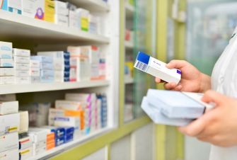 A pharmacist examining medication boxes in a pharmacy setting.