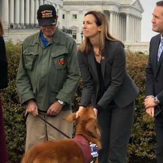 Bipartisan support for the Debra Nixon Special Needs Trust Inclusion Act is shown during a congressional event, featuring a veteran and a representative with a service dog.