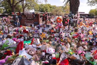 A memorial with flowers, stuffed animals, and signs honoring the victims of the Uvalde school shooting in front of Robb Elementary School.